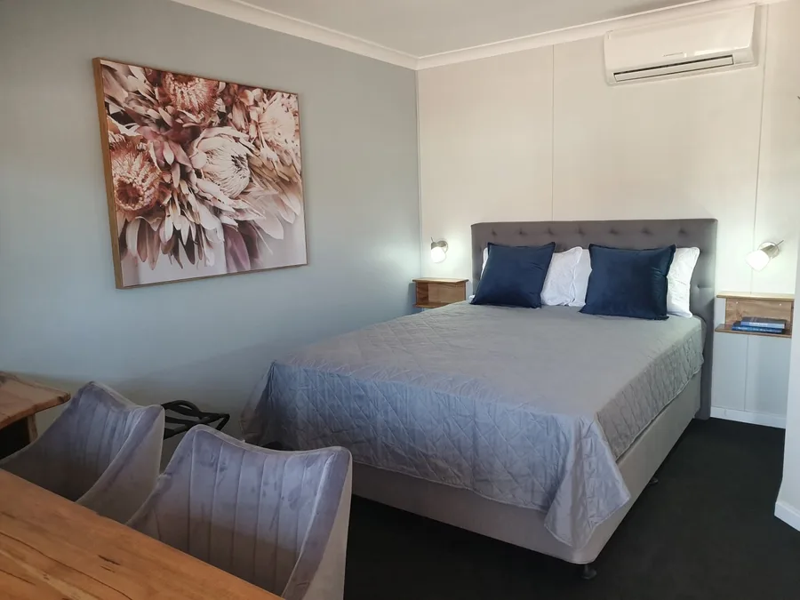 Queen room with grey quilted bedspread and protea artwork